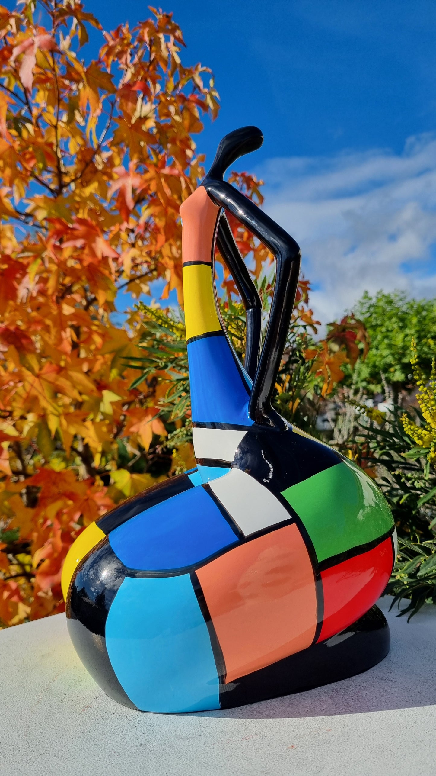 Statue de femme danseuse assise, en résine noire et multicolore, motifs à carreaux. Hauteur 45 centimètres