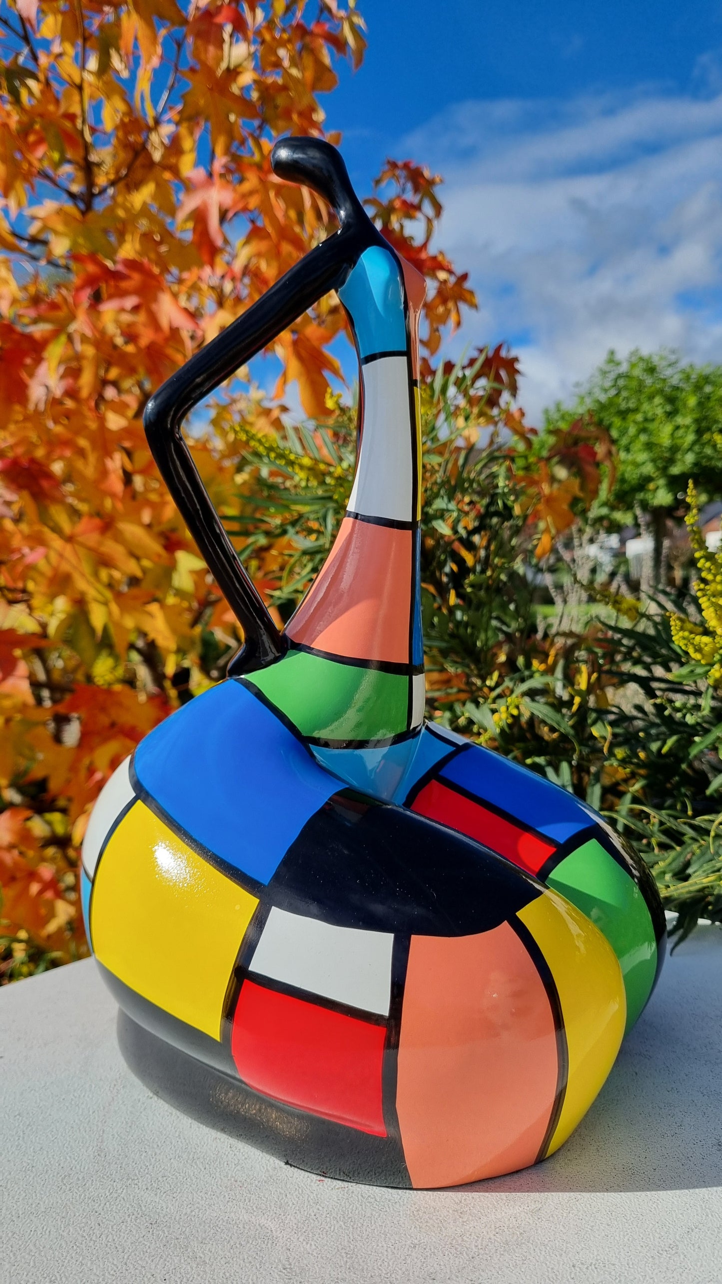 Statue de femme danseuse assise, en résine noire et multicolore, motifs à carreaux. Hauteur 45 centimètres